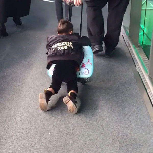 North West getting dragged through the airport on her 'Frozen' bag!